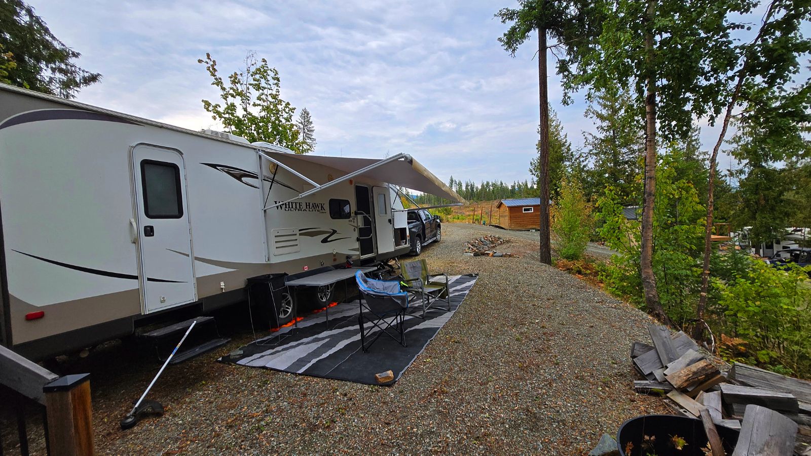 Awning, outdoor mat and camp chairs set up on the site